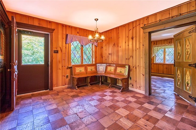 unfurnished dining area with wooden walls and a chandelier