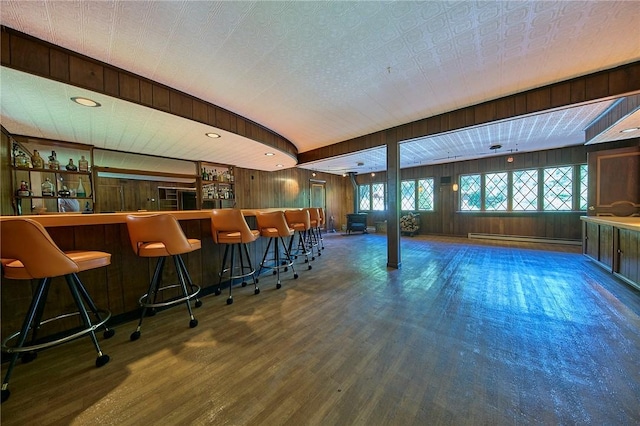 bar with wood-type flooring, wooden walls, and a baseboard heating unit