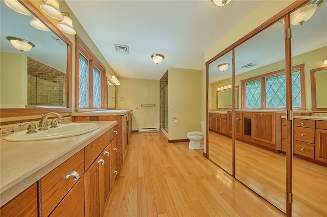 bathroom with walk in shower, vanity, baseboard heating, hardwood / wood-style flooring, and toilet