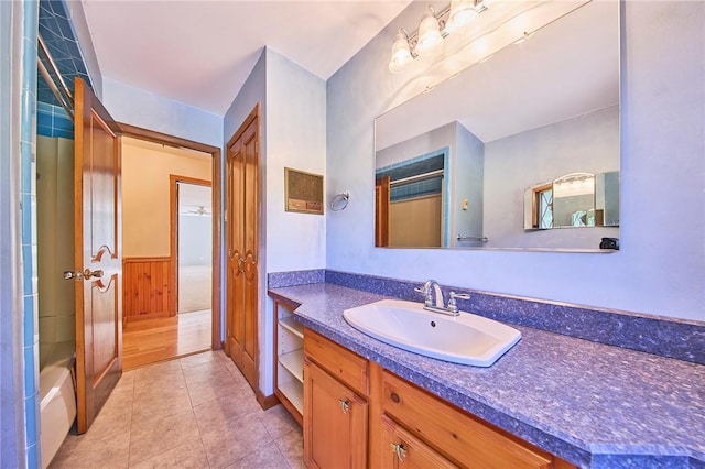 bathroom with tile patterned flooring, vanity, wooden walls, and bathing tub / shower combination