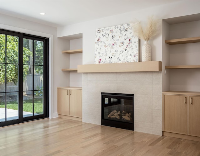 unfurnished living room with a fireplace, built in features, and light hardwood / wood-style flooring