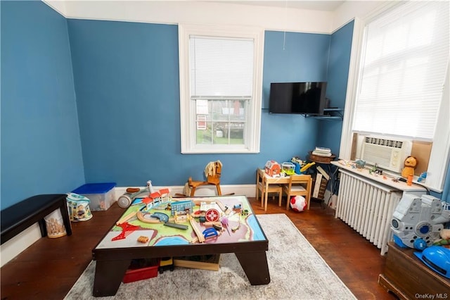 playroom with radiator heating unit, cooling unit, and dark hardwood / wood-style floors