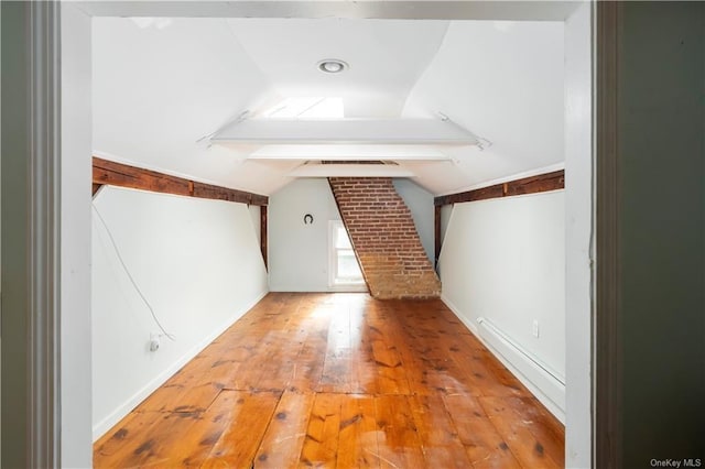 additional living space featuring vaulted ceiling with beams and light hardwood / wood-style flooring