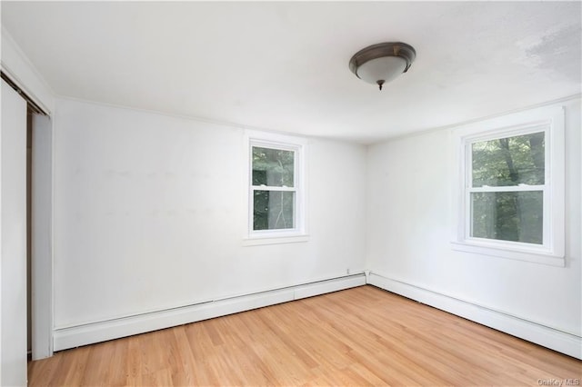 unfurnished room featuring hardwood / wood-style floors and a baseboard heating unit