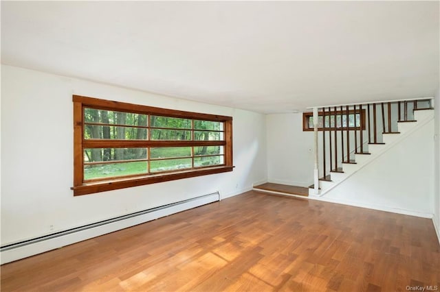 spare room featuring wood-type flooring and a baseboard heating unit