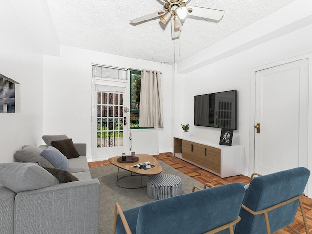 living room with ceiling fan, parquet floors, and a textured ceiling