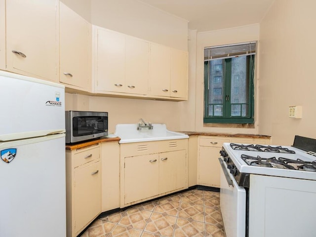 kitchen with white cabinets, white appliances, light tile patterned flooring, and sink