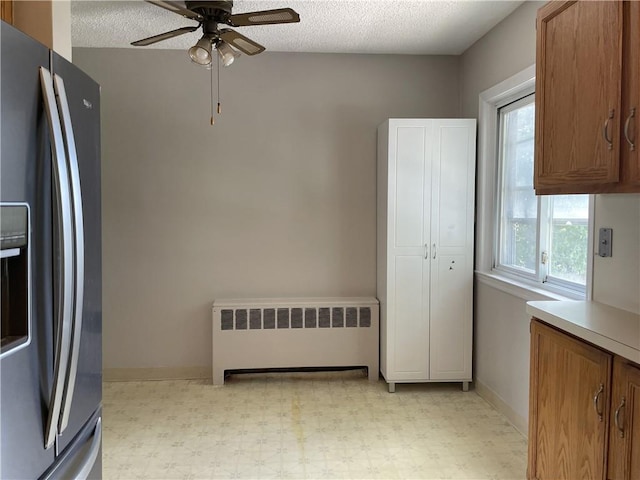 kitchen featuring stainless steel fridge with ice dispenser, a textured ceiling, radiator, and ceiling fan