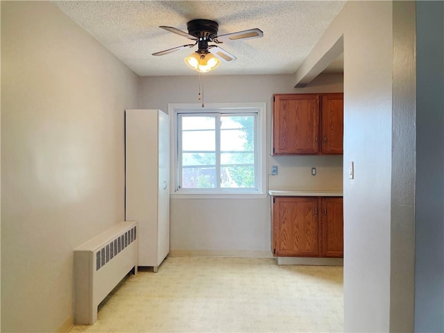 kitchen featuring radiator, ceiling fan, and a textured ceiling