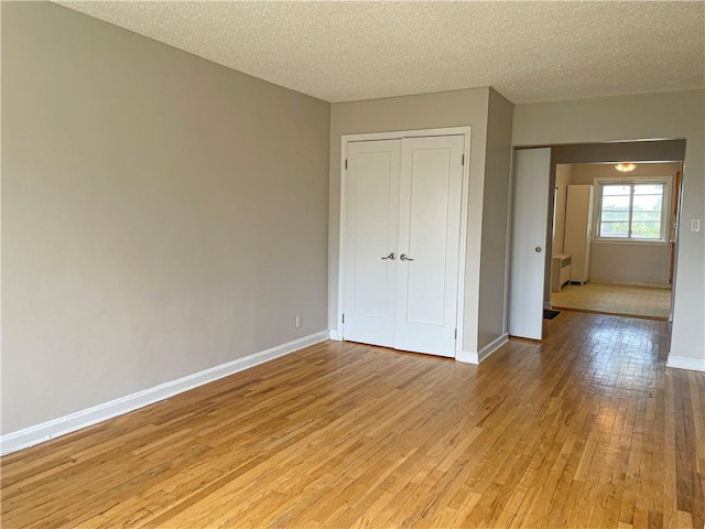 unfurnished bedroom featuring a closet, a textured ceiling, and light hardwood / wood-style flooring