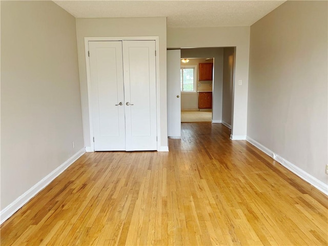 unfurnished bedroom with a textured ceiling, light wood-type flooring, and a closet