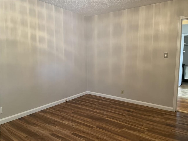 empty room featuring dark wood-type flooring and a textured ceiling