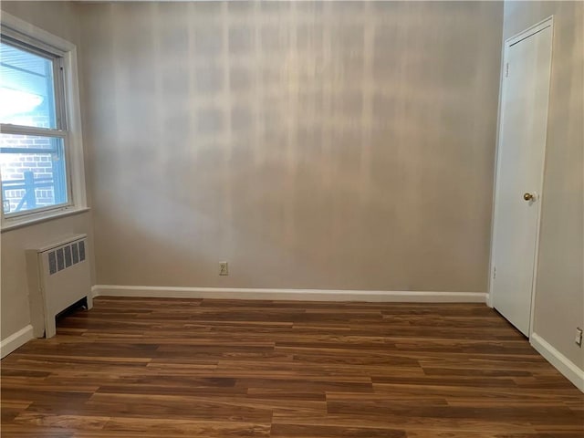 unfurnished room featuring dark hardwood / wood-style flooring and radiator