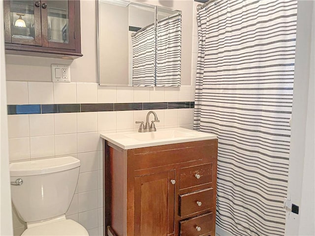 bathroom featuring vanity, toilet, tile walls, and walk in shower