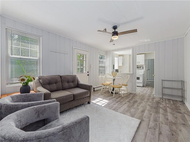 living room with ceiling fan, light hardwood / wood-style floors, and a baseboard heating unit