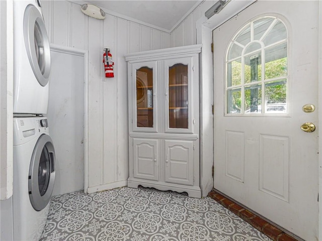 washroom featuring stacked washing maching and dryer and crown molding