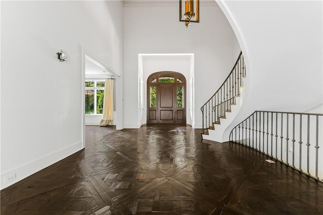 foyer featuring dark parquet flooring and a high ceiling