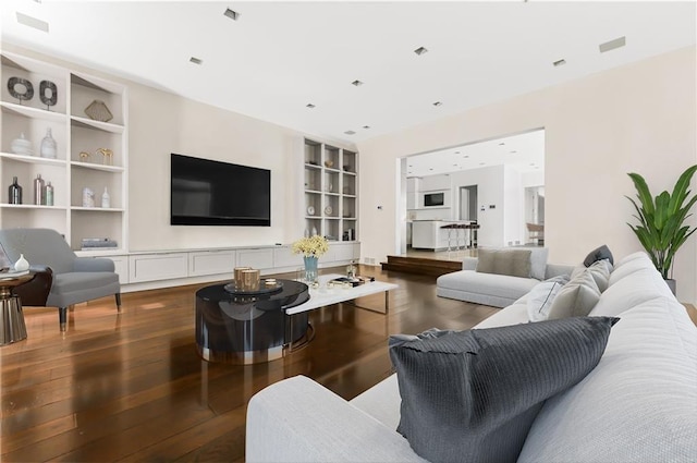 living room featuring built in shelves and dark wood-type flooring