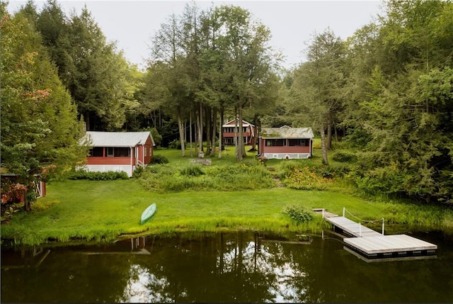 view of dock with a yard and a water view