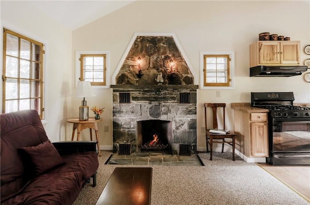 carpeted living room featuring a stone fireplace, plenty of natural light, and lofted ceiling