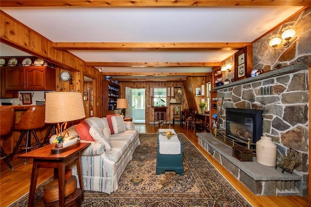 living room with beamed ceiling, wood-type flooring, a fireplace, and wooden walls