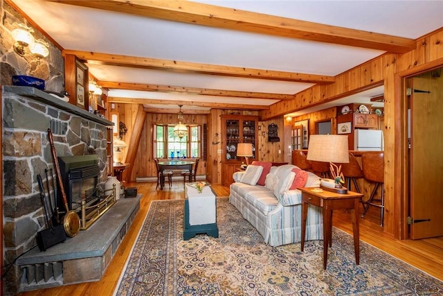 living room featuring beamed ceiling, wood-type flooring, and wooden walls