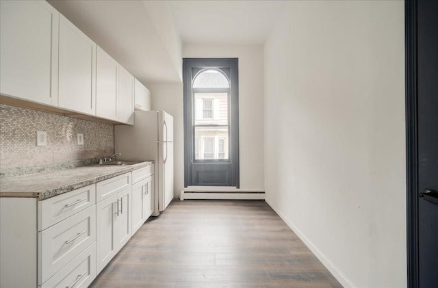 kitchen with white cabinets, decorative backsplash, light hardwood / wood-style flooring, and a baseboard radiator