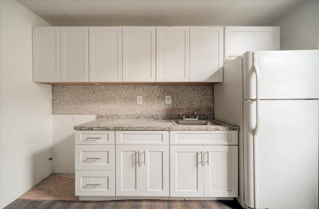 kitchen with white fridge, white cabinetry, hardwood / wood-style flooring, and sink