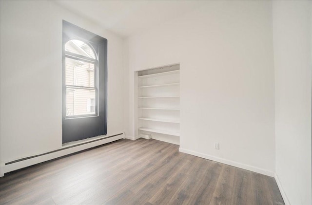 unfurnished room featuring hardwood / wood-style flooring and a baseboard heating unit