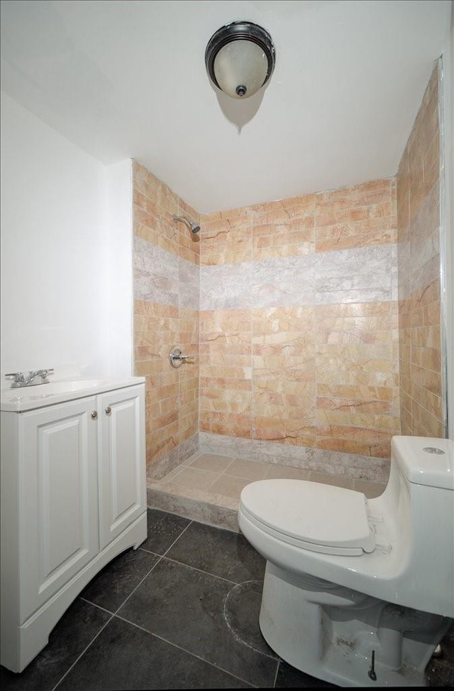 bathroom with tiled shower, sink, tile patterned flooring, and toilet