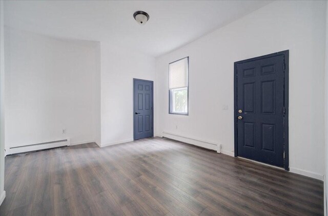 empty room featuring dark wood-type flooring and a baseboard heating unit