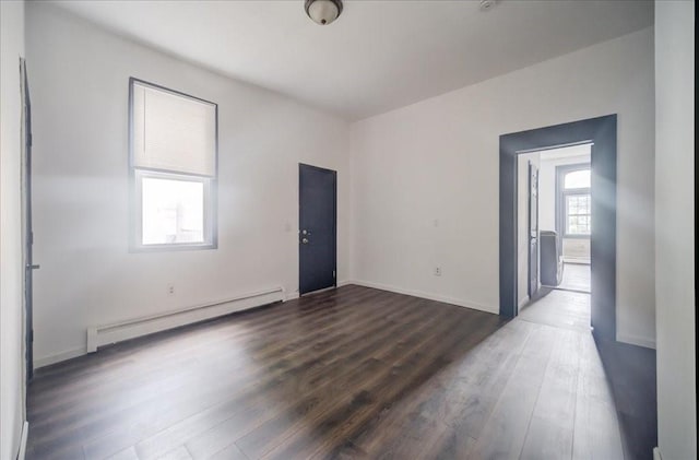 spare room featuring dark wood-type flooring and a baseboard heating unit