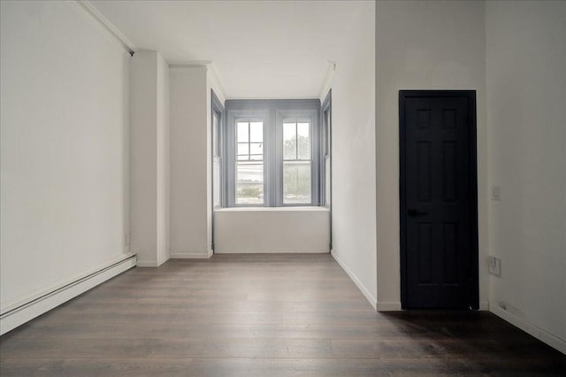 empty room featuring ornamental molding, dark wood-type flooring, and a baseboard heating unit