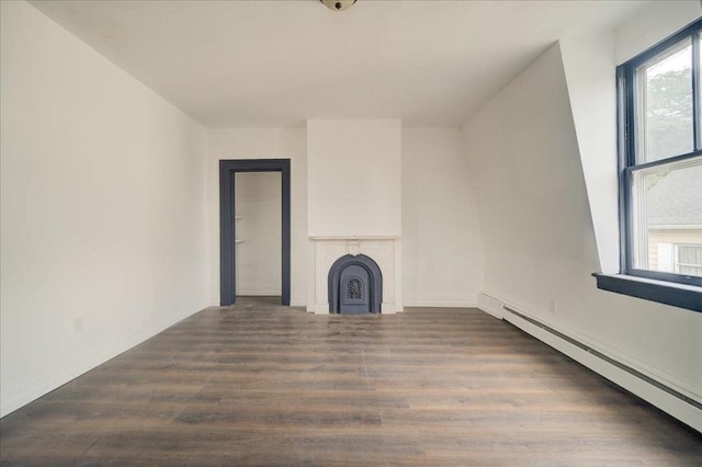 unfurnished living room with dark wood-type flooring and a baseboard heating unit