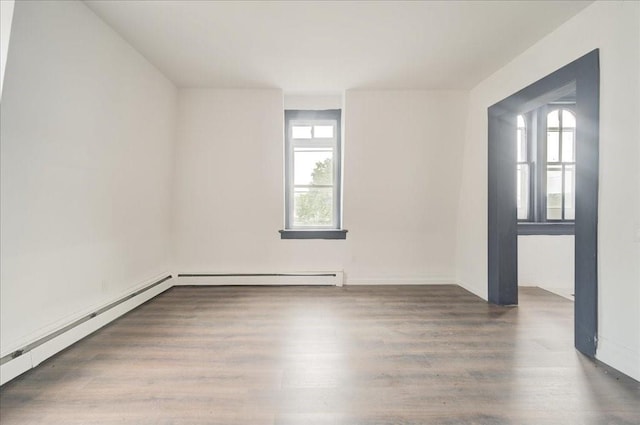 unfurnished room with dark hardwood / wood-style floors and a baseboard heating unit