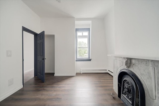 unfurnished living room with a baseboard heating unit and dark wood-type flooring