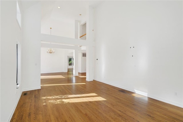 interior space with a chandelier, a towering ceiling, and wood-type flooring