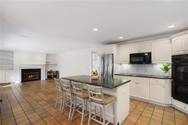 kitchen with backsplash, a center island, white cabinets, and black appliances