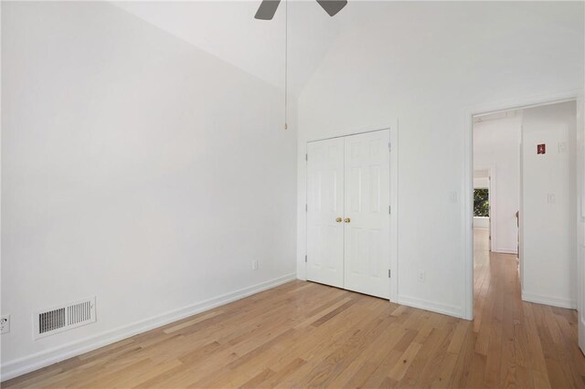 empty room featuring ceiling fan, high vaulted ceiling, and light wood-type flooring