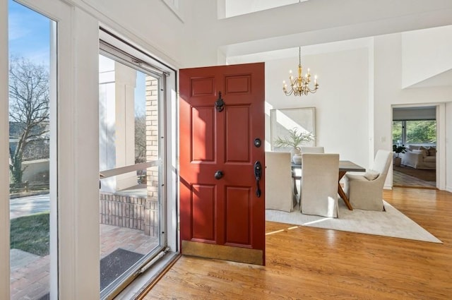 entrance foyer with a towering ceiling, an inviting chandelier, and light hardwood / wood-style floors