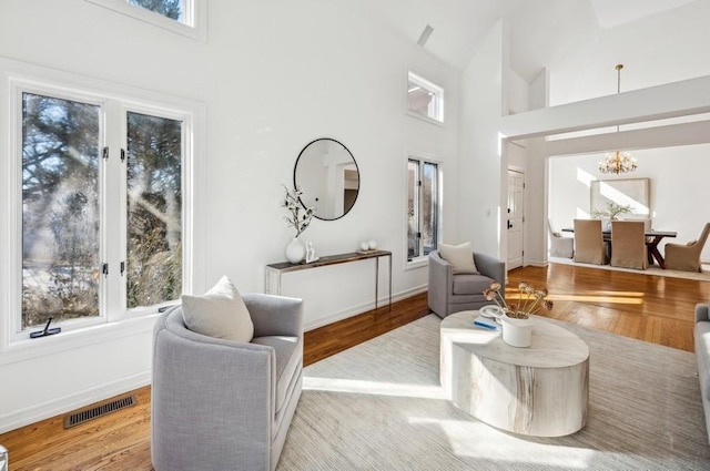 living room with high vaulted ceiling, an inviting chandelier, and light hardwood / wood-style floors