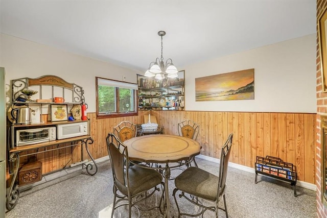 carpeted dining space featuring an inviting chandelier and wood walls