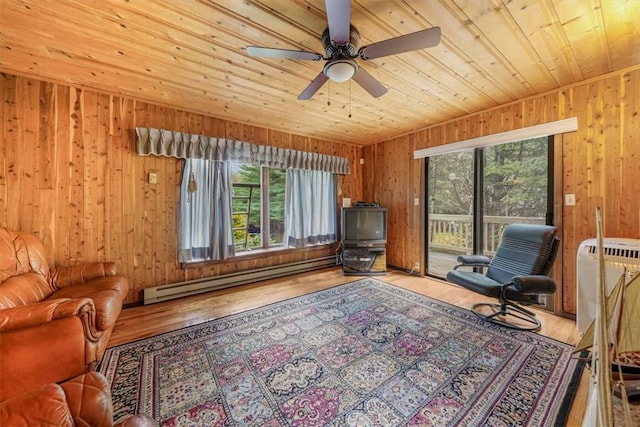 sitting room featuring wooden ceiling, a baseboard heating unit, wooden walls, hardwood / wood-style flooring, and ceiling fan