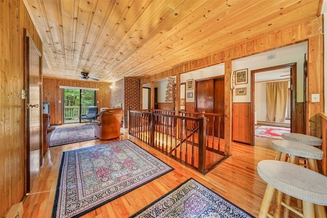 corridor featuring light hardwood / wood-style floors, wood ceiling, wooden walls, and a baseboard heating unit