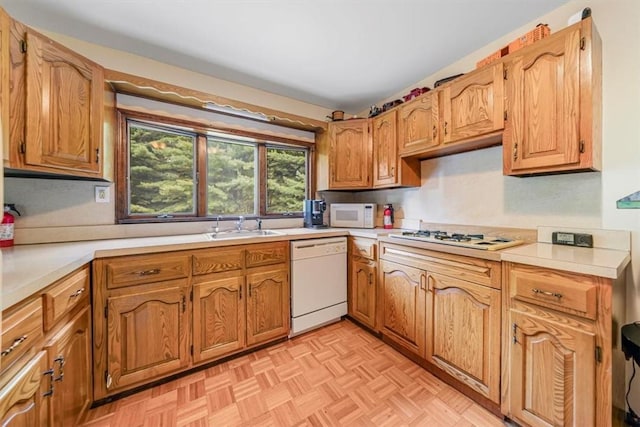 kitchen featuring white appliances, light parquet floors, and sink