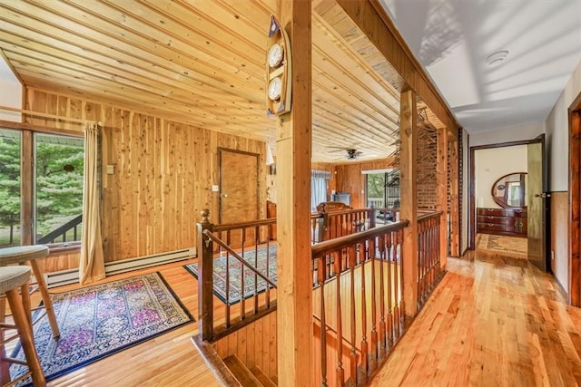 hallway featuring hardwood / wood-style flooring, wooden walls, and a baseboard radiator