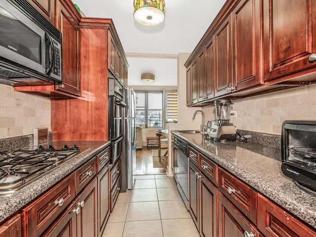 kitchen with sink, light tile patterned flooring, dark stone countertops, and stainless steel appliances