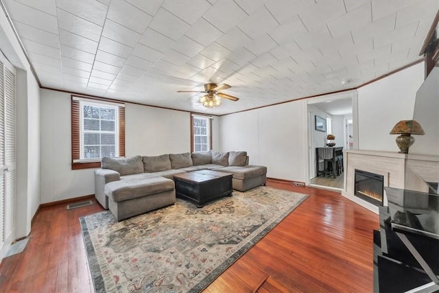 living room featuring ceiling fan, crown molding, and dark wood-type flooring