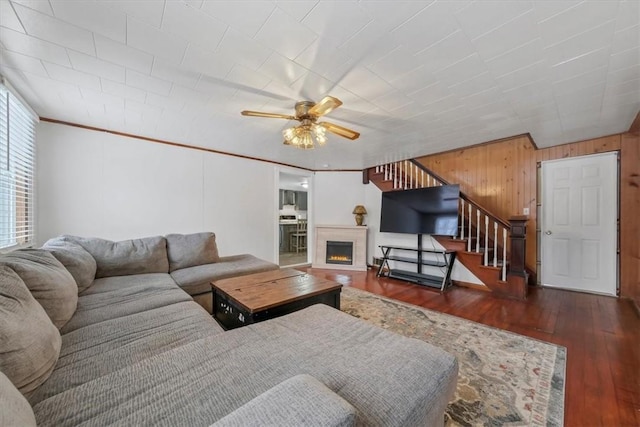 living room with wood walls, dark hardwood / wood-style floors, and ceiling fan