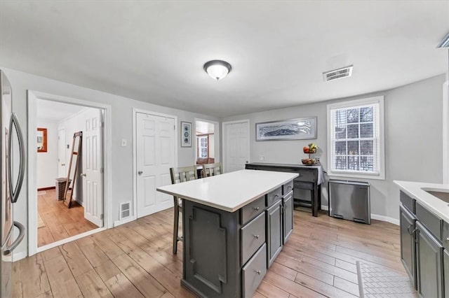 kitchen featuring stainless steel fridge, a kitchen breakfast bar, a center island, and light wood-type flooring